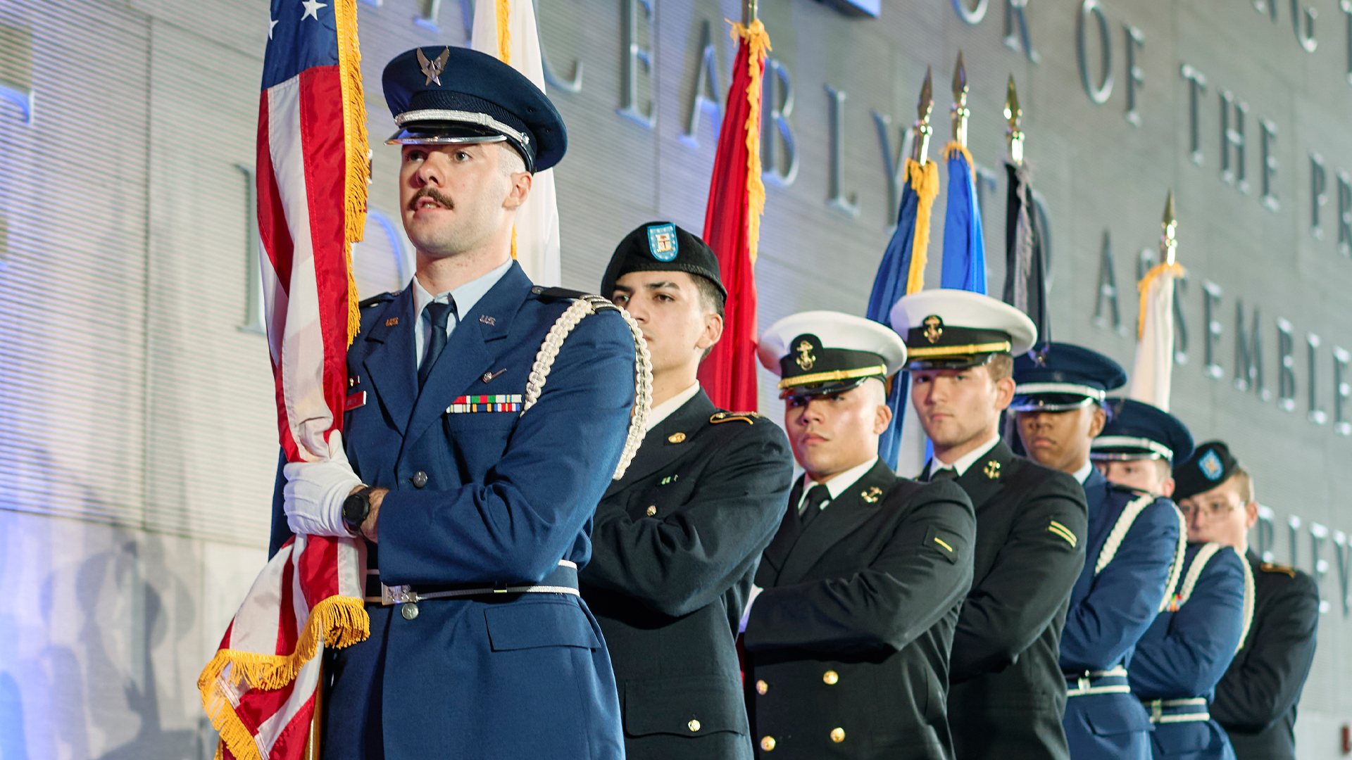 Military servicemen standing in a line holding the flag