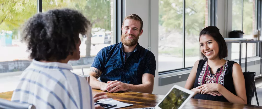 Chartered Life Underwriter advising a young couple in the office