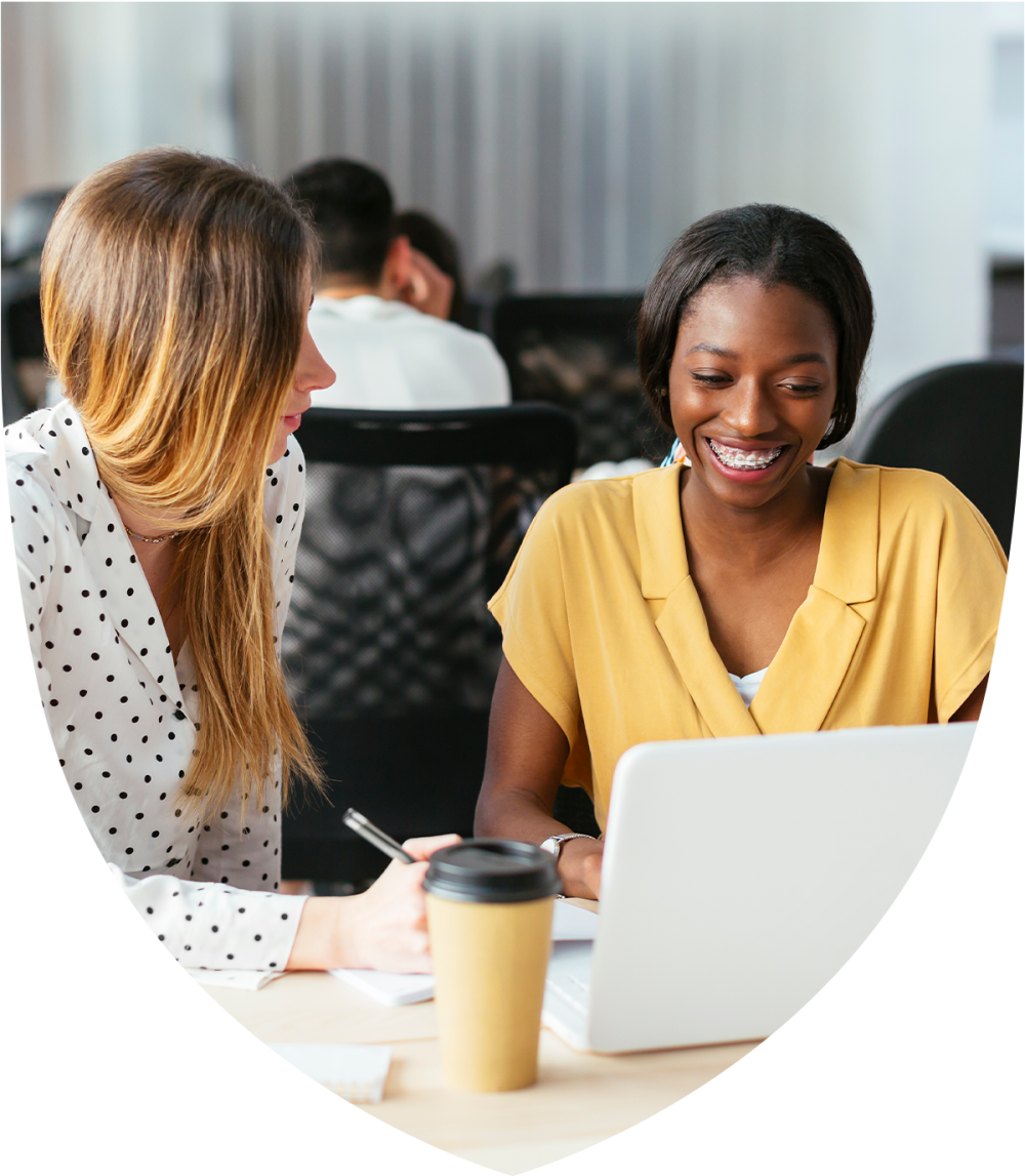 Two women talking while looking at a laptop