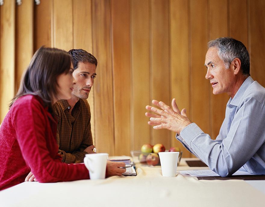 A couple talking to a man across a table