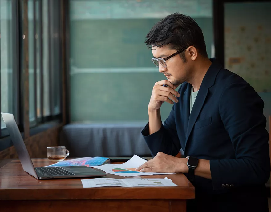 Man working at a desk with a laptop and papers