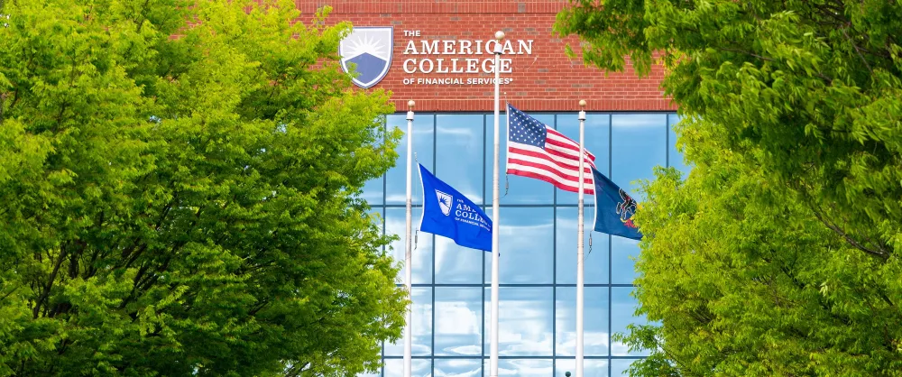 The American flag and college flag outside of the college headquarters