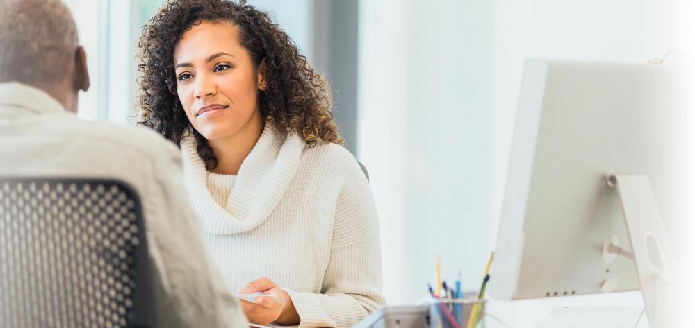 Woman talking to a man next to a desktop