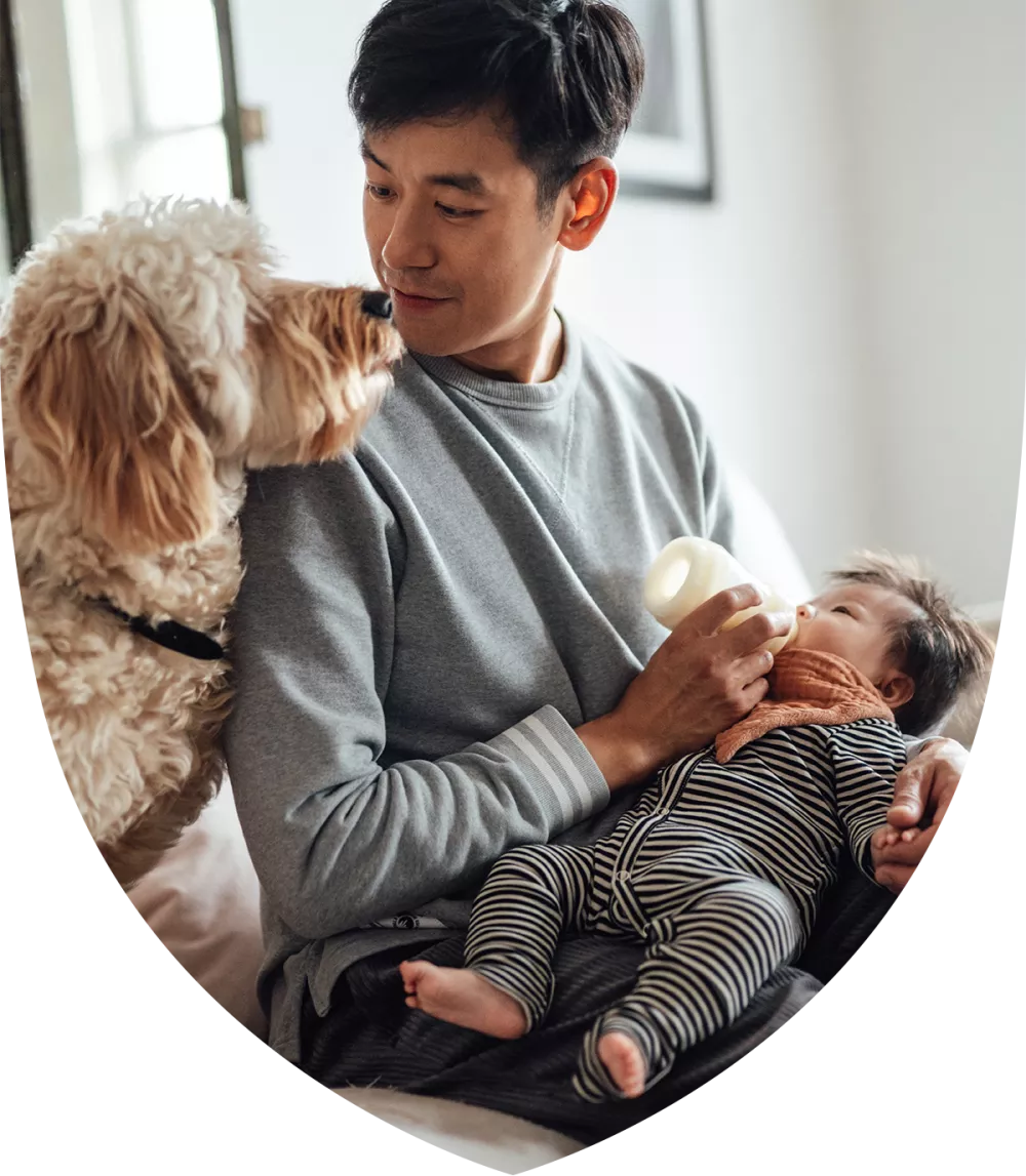 A man holding a baby and a dog over his shoulder