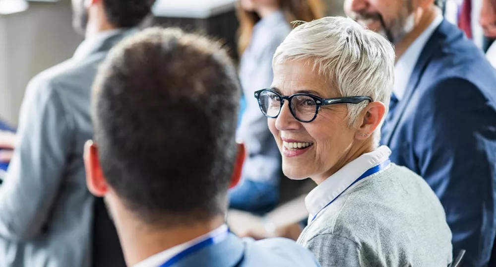 Two colleagues smiling and talking together at a conference