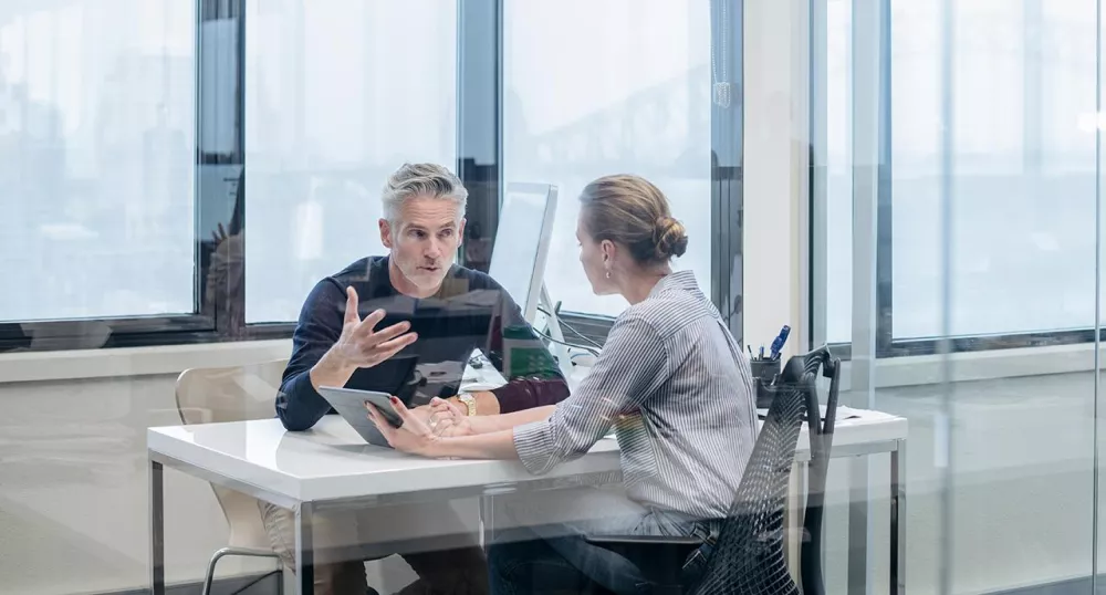 Male and female colleagues sitting and talking together in the office