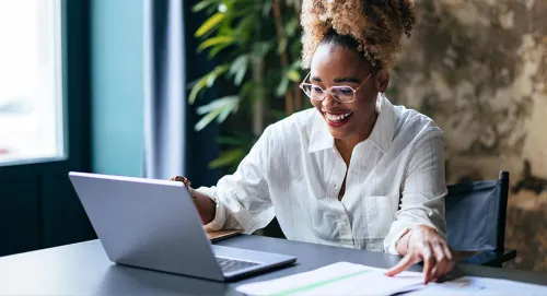Female in her late 20's sitting at the computer and smiling